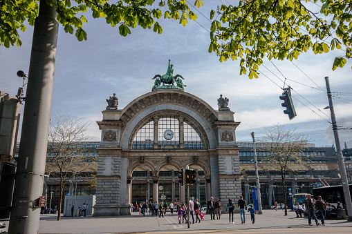Lucerne, Switzerland - April 20, 2014: People go through arch main entrance to Lucerne railway station. Lucerne is a famous tourist destination due to its location within sight of Swiss Alps