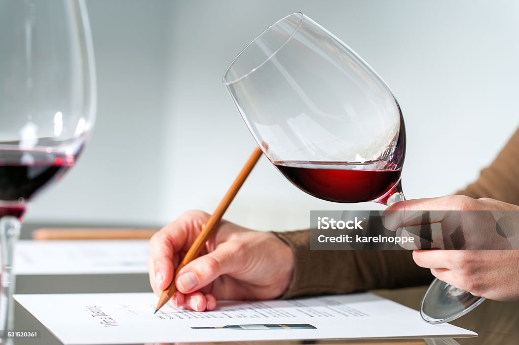 Sommelier evaluating red wine. Extreme close up of sommelier evaluating red wine in wine glass at tasting. Wine Stock Photo