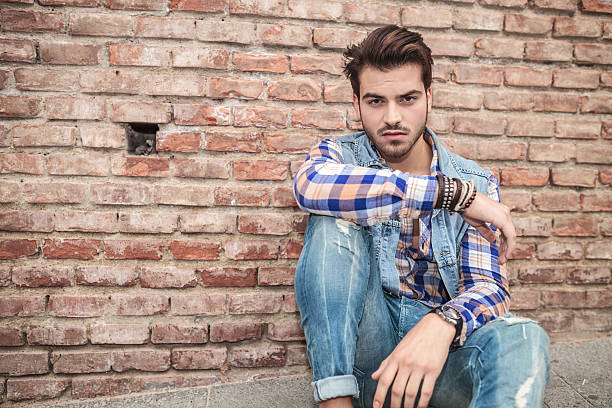 istock young man sitting near a brick wall, resting 531521083