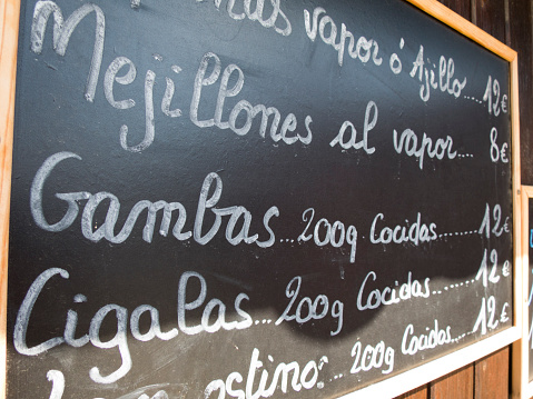 black placards spanish handwritten in brown wood wall with typical menu food dishes in spanish