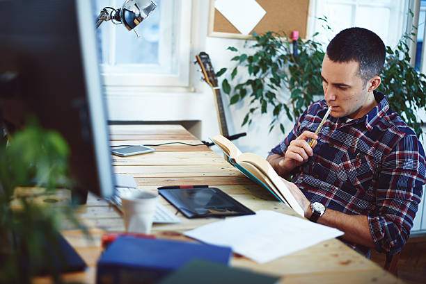 Young man in home office reading book