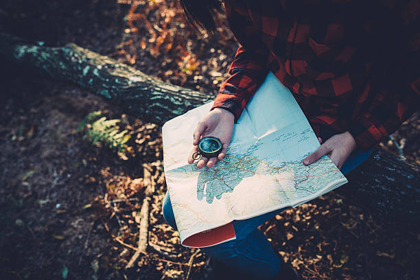 Teenager girl with Compass Reading a Map in the forest stock photo