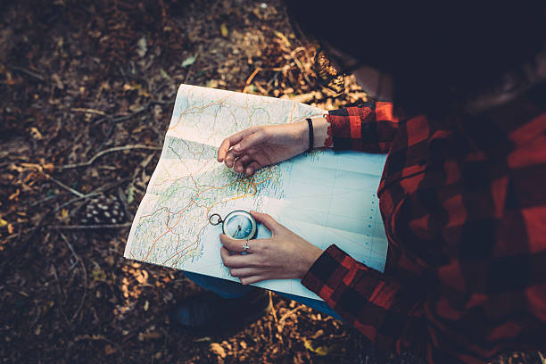 Teenager girl with Compass Reading a Map in the forest stock photo