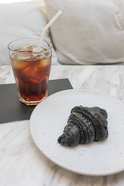 istock iced coffee and black color croissant 531534700