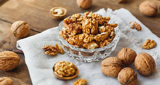 Photo of Glass bowl with walnuts on rustic homespun napkin. Healthy snack.