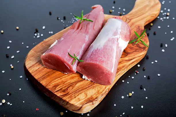 Photo of Fresh Raw pork tenderloin on wooden board .ready to cook
