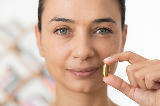 woman holding とソフトなジェルを発表 - fish oil pill healthy lifestyle protection ストックフォトと画像