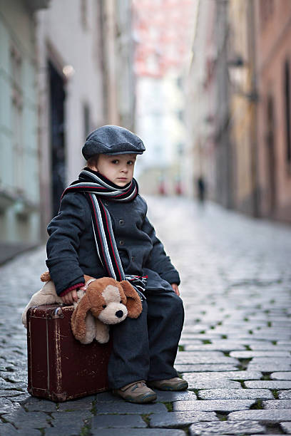 istock Cute boy, sitting on a suitcase, holding a teddy bear 531537543