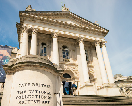 London, UK - May 1, 2016: Close-up of a sign at the foot of the steps leading to the front entrance of the Tate Britain art gallery, with a couple about to enter the building.