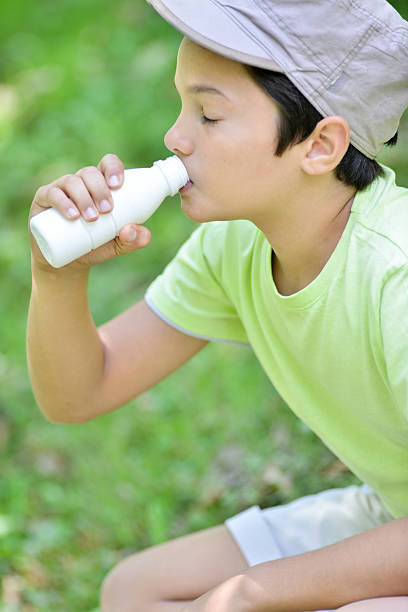 istock teYoung boy sitting in the grass drinking milk drink 531545518