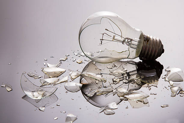 Broken light bulb on shiny surface stock photo