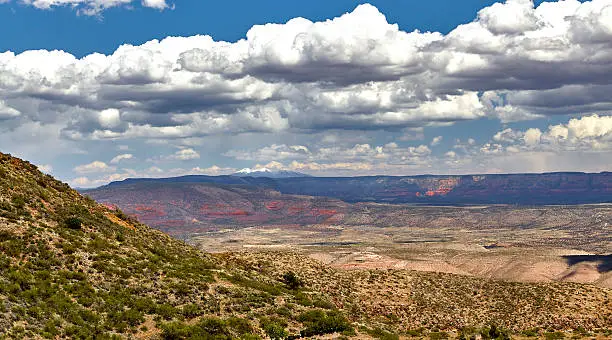 View of red rock mountains in Sedona Arizona with snow capped San Francisco Peaks in Flagstaff Arizona taken from mountaintop in Jerome Arizona