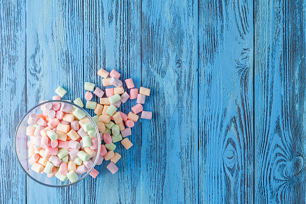 istock Glass bowl of colored marshmallows, on blue background 531551506