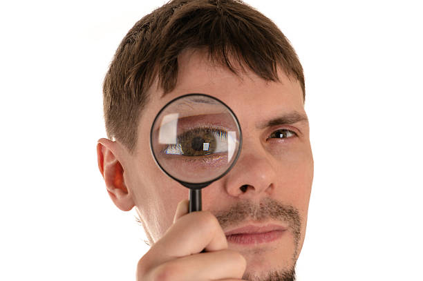 istock young man looking through a magnifying glass giant eye 531552270