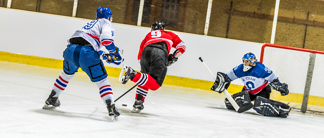 Ice hockey players and goalkeeper in action.