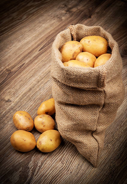 Raw potatoes in the sack on wooden background