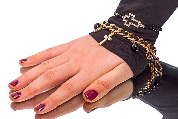 Female hands with trendy dark nail design in gold bracelets on trendy magenta color of year 2023 background. Luxury manicure concept.