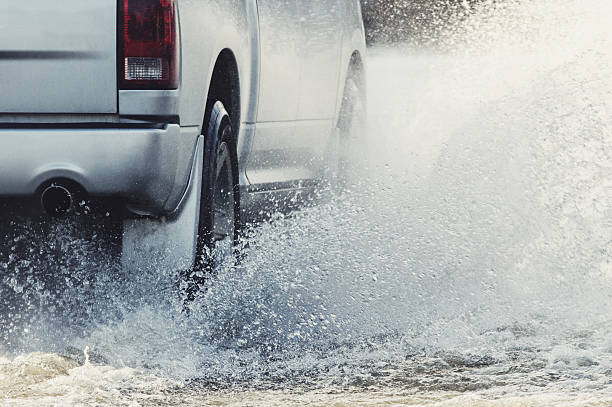 Charging Through Flood Waters A pickup truck plows through flood waters on a rural road. truck rain stock pictures, royalty-free photos & images