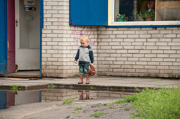 little boy walking through the puddles in rubber boots