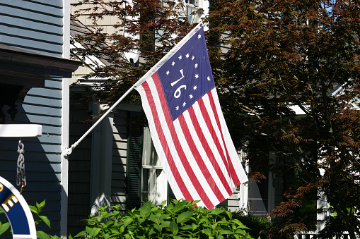 A bicentennial flag waving on the outside of a house