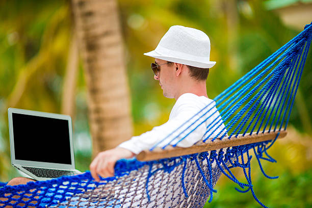 istock Young man with laptop at hammock on tropical vacation 531602806
