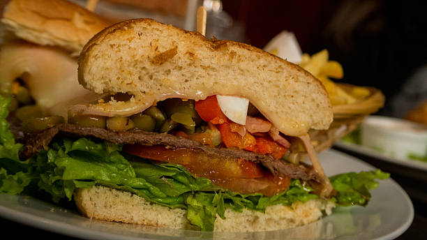 Uruguayan Chivito OLYMPUS DIGITAL CAMERAChivato is an uruguayan beef sandwich, that includes lettuce, tomato, bacon, ham, red pepper, fried eggs, mozzarella cheese, olives and depending on the restaurant more ingredients. cedar waxwing stock pictures, royalty-free photos & images