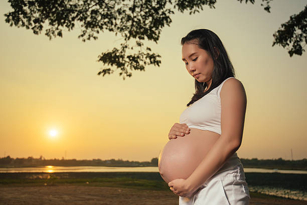istock Pregnant woman standing is relaxing lakeside sunset background 531605948