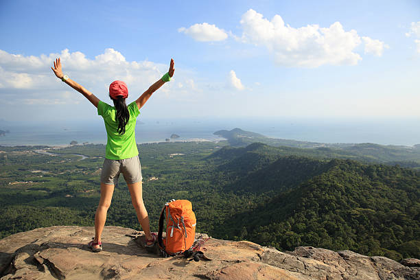 istock cheering successful woman hiker open arms at mountain peak 531608046