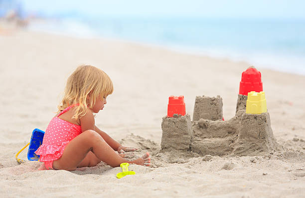 istock little girl play with sand on beach 531608100