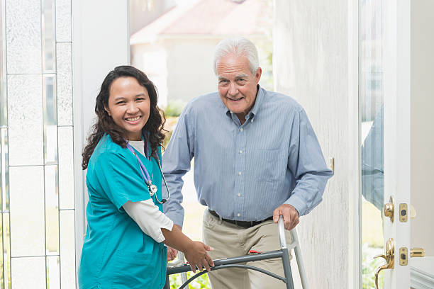 istock Home healthcare worker helping elderly man with walker 531609890