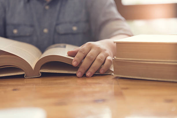 istock woman's hand reading book on wooden table 531610564