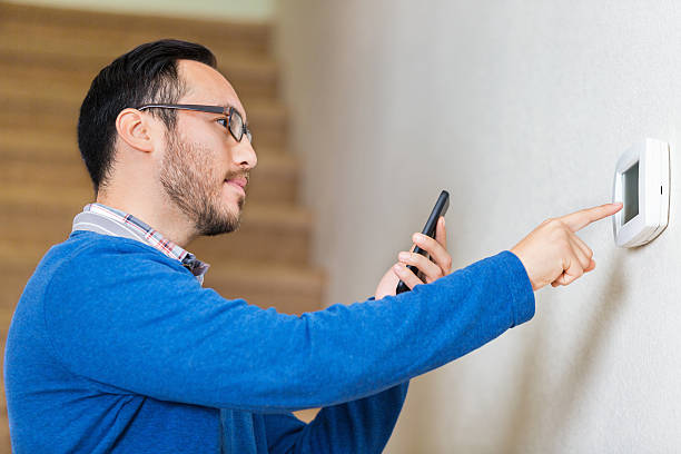 Hispanic man adjusts thermostat at home