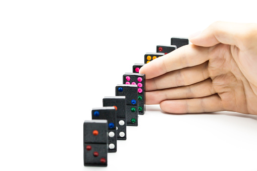 Businessman hand stopping domino effect on isolated white background with copy space - business solution, strategy and successful intervention concept