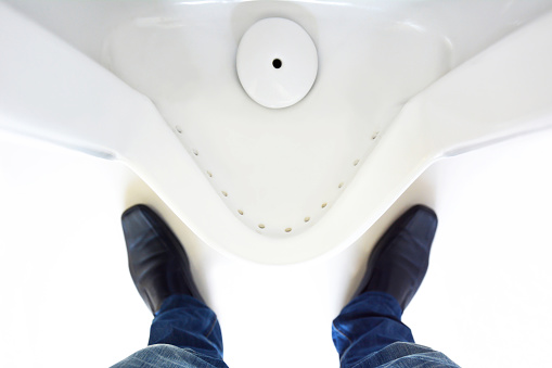 Top view of a man legs in front of urinal in men toilet
