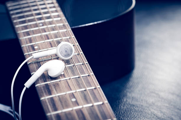istock white earphones on acoustic guitar fingerboard 531616020