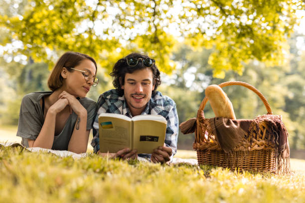 istock Smiling couple enjoying on picnic and reading a book. 531618890