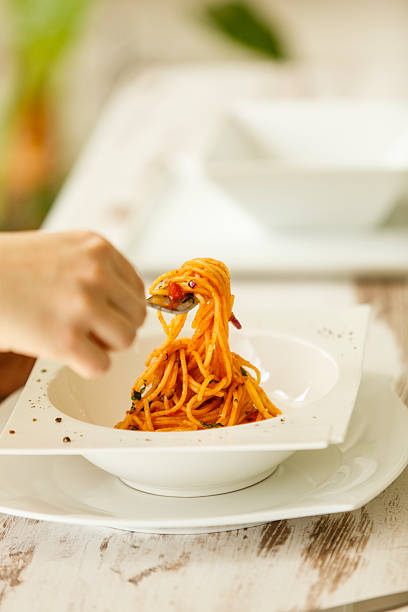 istock Woman twirling spaghetti on fork, close-up of hands 531619706