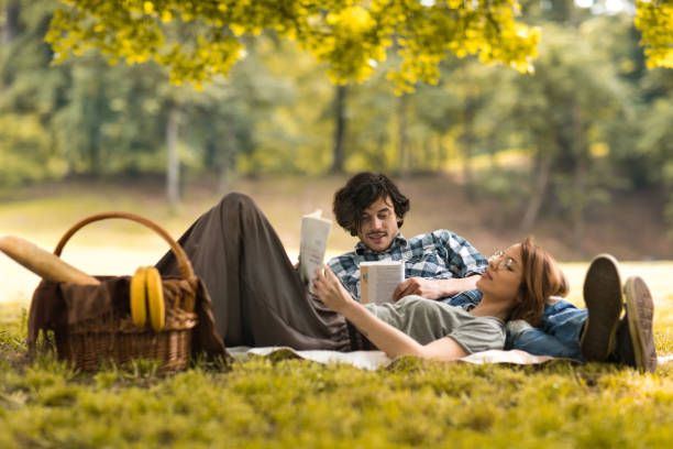 istock Relaxed couple reading books on picnic during springtime. 531620428