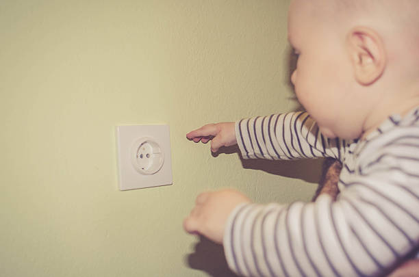 istock Dangerous baby sticking fingers into electrical outlet 531624178