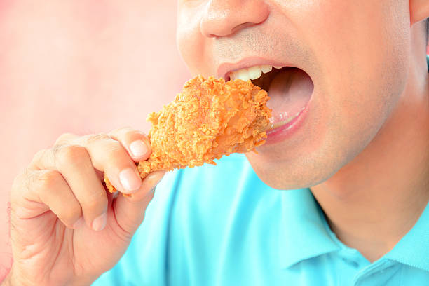 l'uomo mangiando pollo fritto gamba o bacchetta del tamburo - deep fried people fried chicken foto e immagini stock