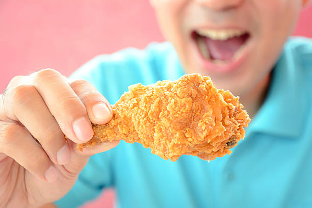 istock Young man holding  fried chicken leg, about to eat 531626195