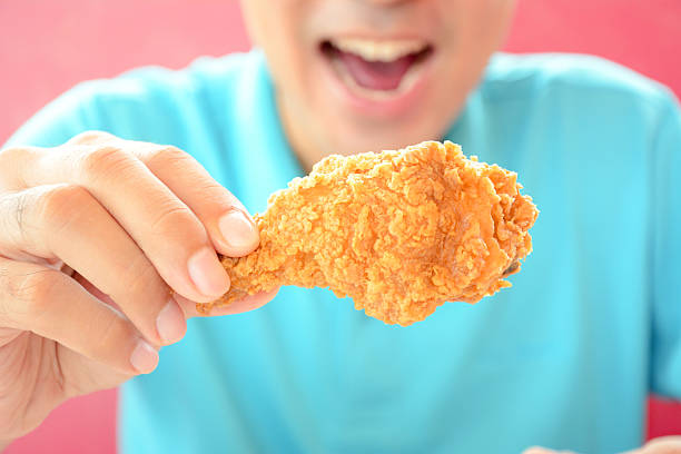 giovane uomo con pollo fritto gamba, per mangiare - deep fried people fried chicken foto e immagini stock