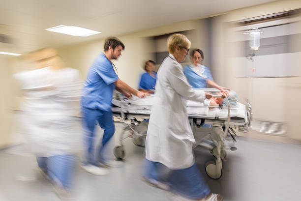 Doctor wheeling patient Doctors and nurse wheeling patient on stretcher in hospital's corridor. emergency room photos stock pictures, royalty-free photos & images