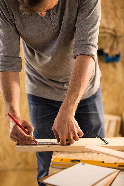 istock Carpenter measuring and marking wooden plank 531627256