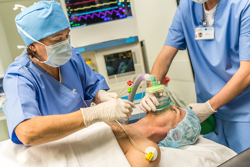 Anesthesiologist using oxygen mask on patient in operating theatre.