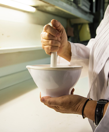 Scientist grinds up compound in porcelain mortar using a pestle
