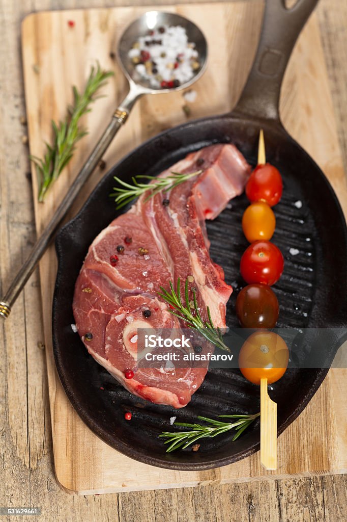 Raw lamb chops Raw lamb chops with cherry tomato and rosemary herb ready to cook. Selective focus. 2015 Stock Photo