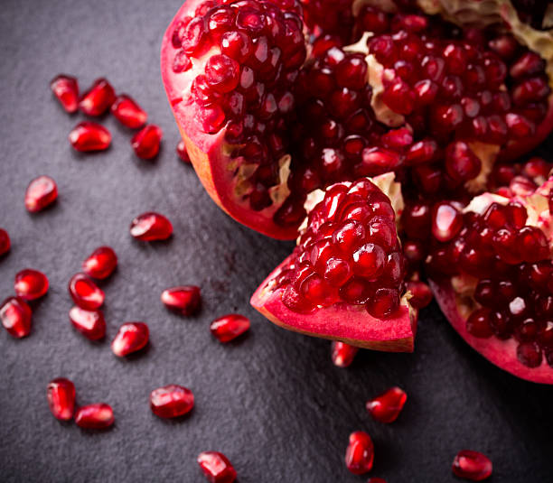 istock Some red pomegranates on black slate plate 531632051