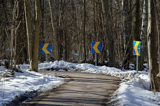 Roadsigns in a curve at a biking trail at wintertime in the forest
