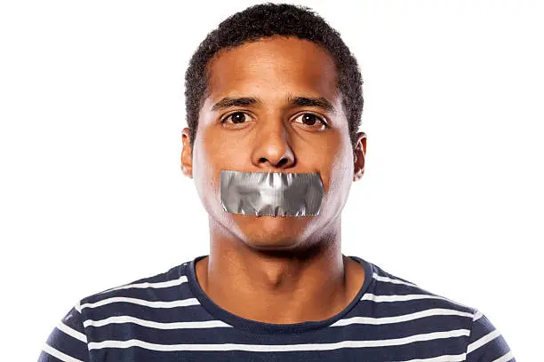 Photo of Dark-skinned young man with adhesive tape over his mouth